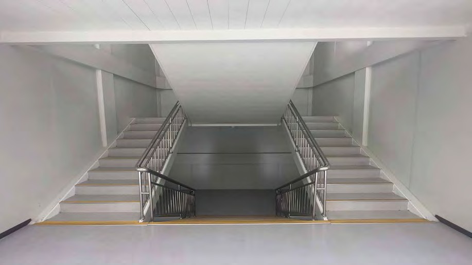 Internal switchback stair in a modular building with steel handrails, a mid landing and a flat ceiling